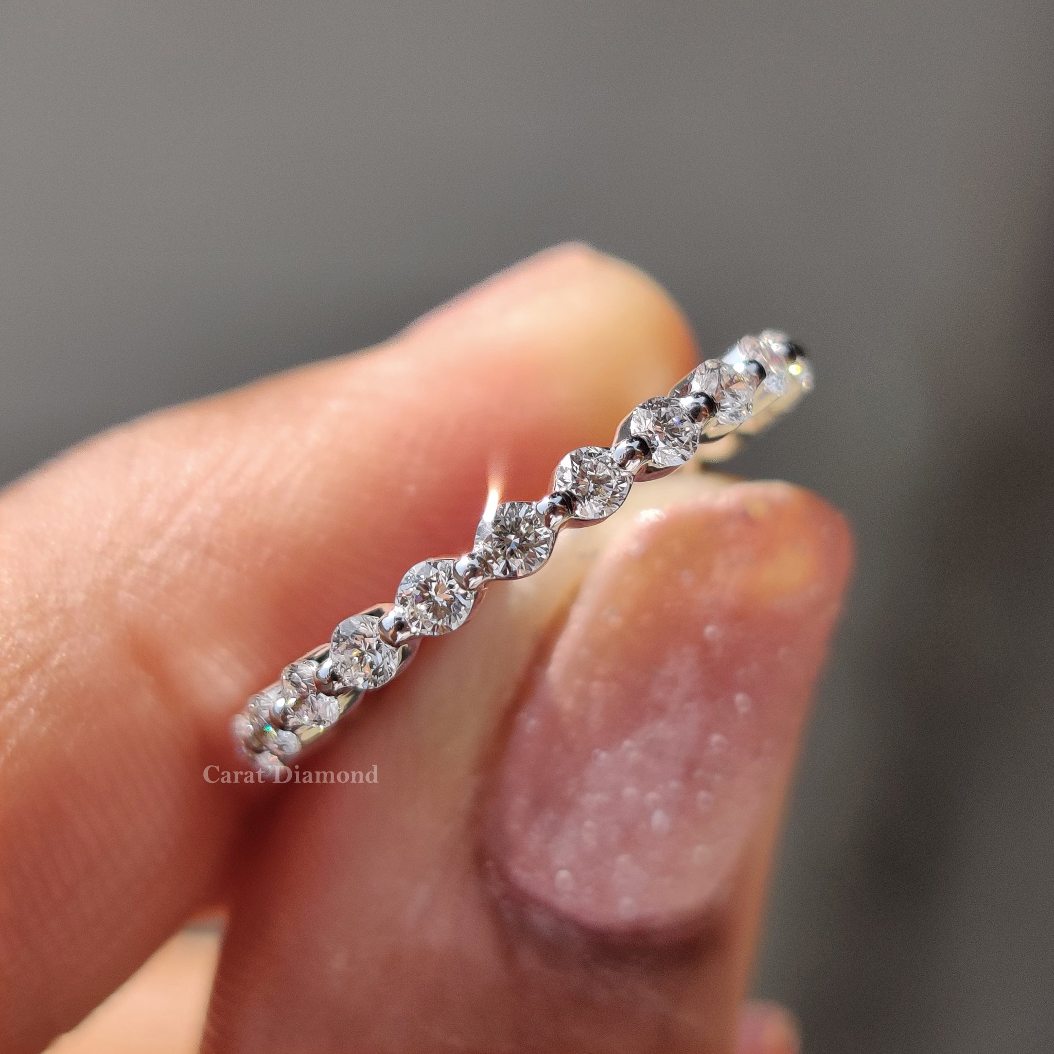 Elegant eternity wedding band with round cut diamond in a shared prong set, crafted in white gold for timeless beauty.